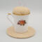 This is the back of the teacup showing different flowers and sitting on the trivet.